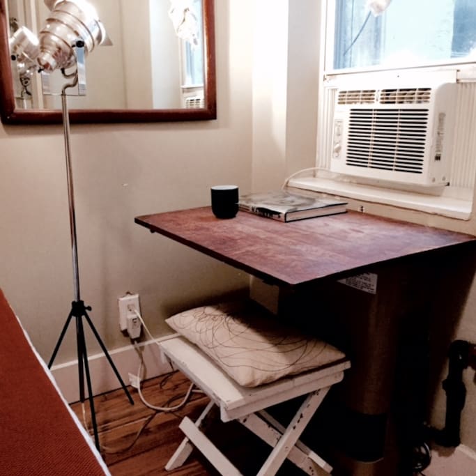 A desk, lamp and a mirror in front of the window for when you get ready for that NY night out.