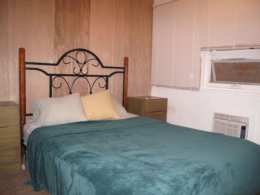very small bedroom with a loud a/c, small window, and a ceiling fan
