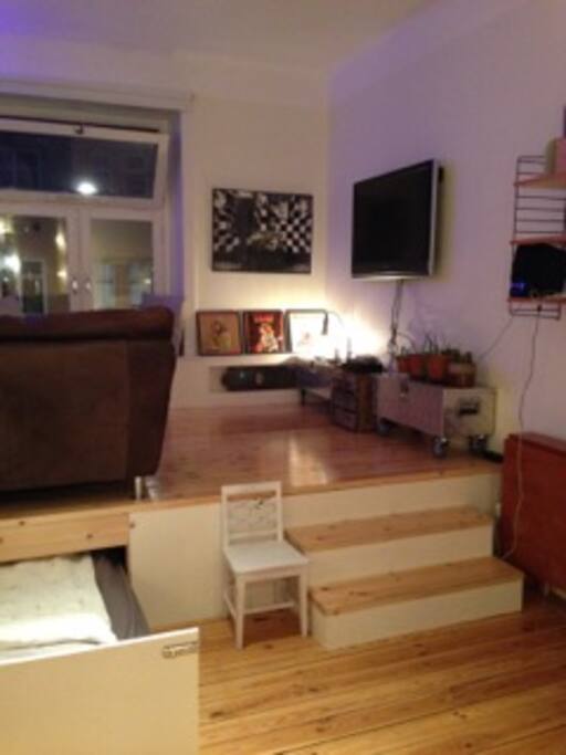 Stage with sofa and armchair. Bed 160 cm is rolled in underneath the stage. When it´s bedtime one roll it out!