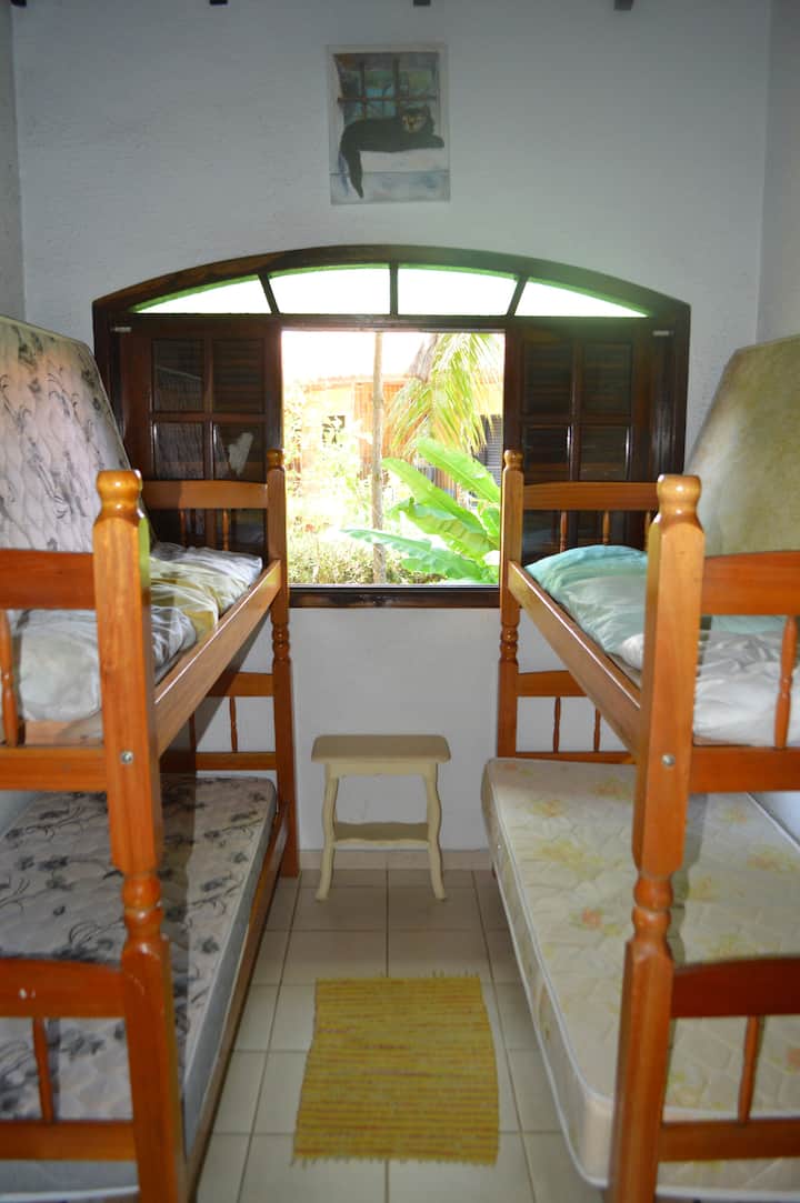 Ოთახის ხედი ორი ორსართულიანი საწოლითა და ექვსი ბალიშით. Არის ორი პატარა გვერდითი მაგიდა და სარკე.