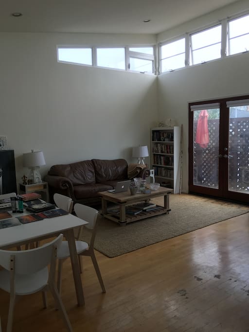 Main living room with 14 ft ceilings, french doors to wrap around patio, large couch & 4 person dinning table