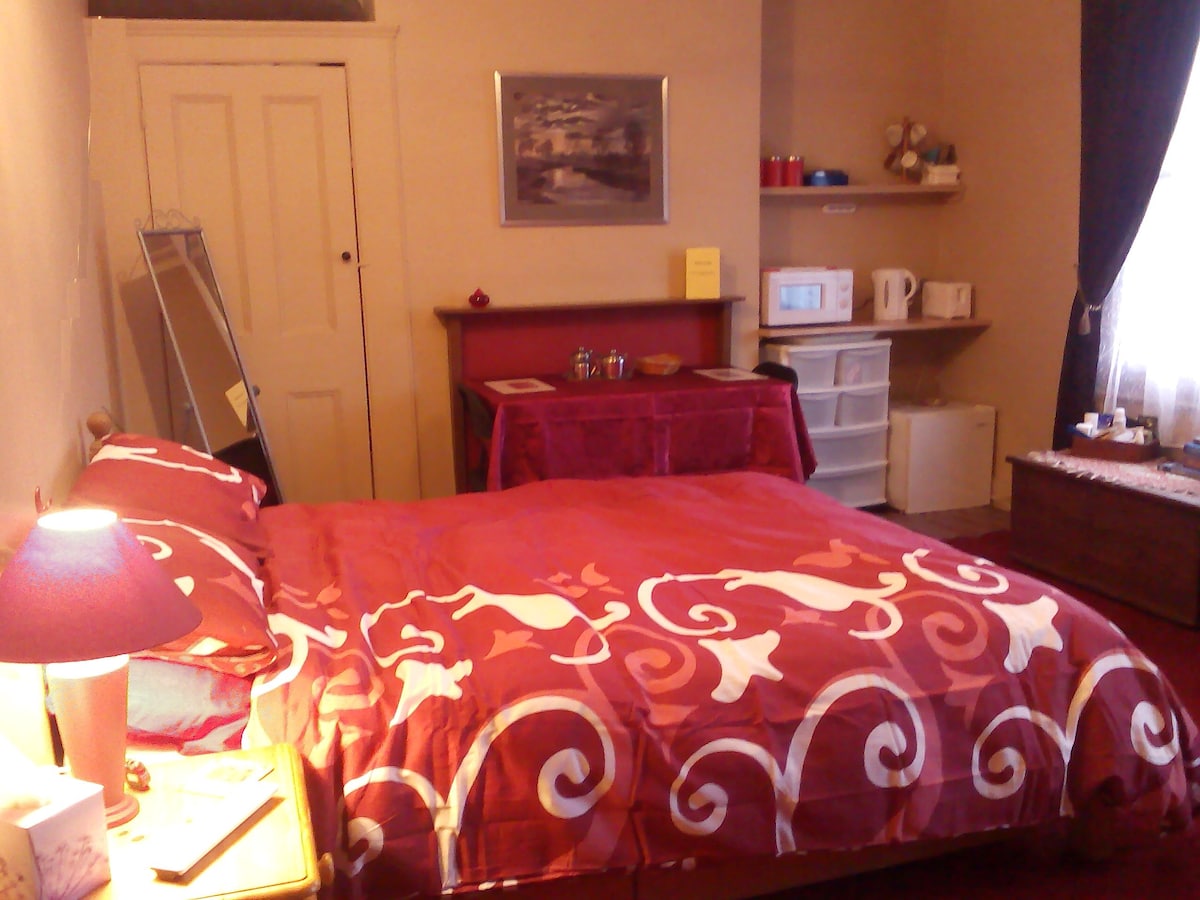 Amplia habitación con cama tamaño king, mesa y suministros para el desayuno en la habitación.