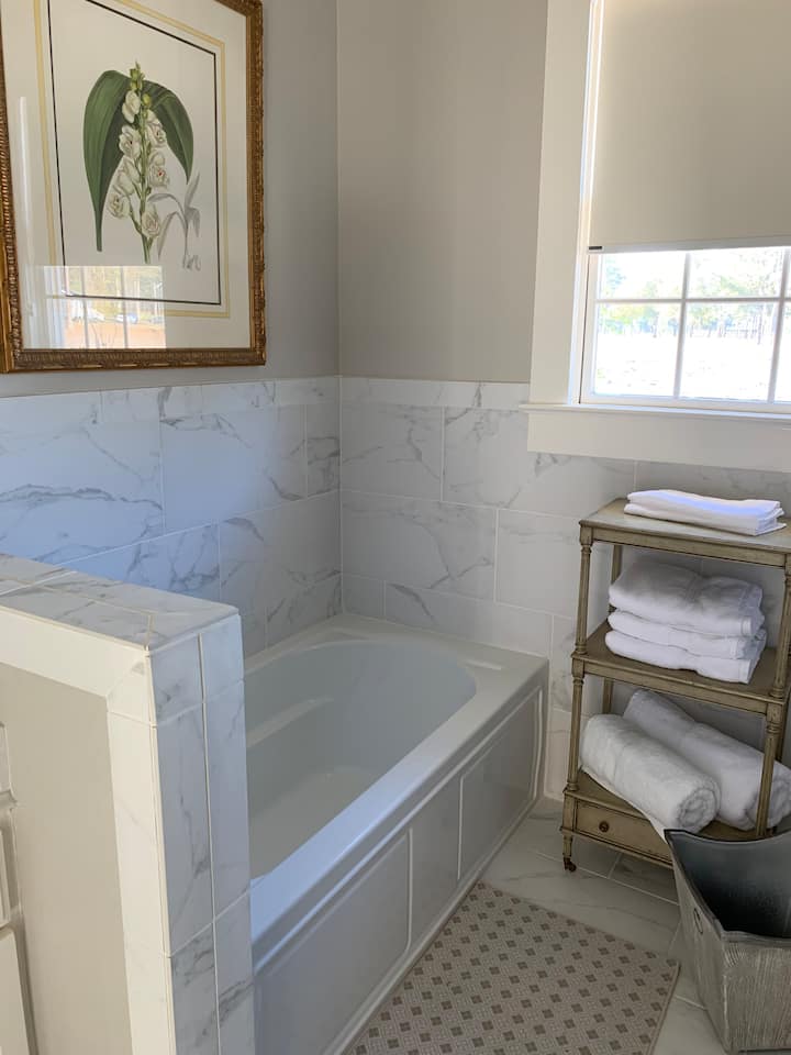 The Magnolia Rooms spa-like bathroom has a newly tiled stand up shower with massaging shower head, full size tub, double vanity and a water closet. 