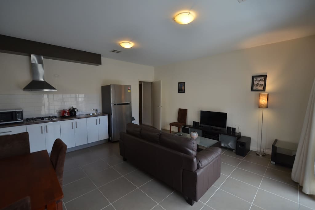Living room and kitchenette. The living room features a 32" flat screen TV with an Onkyo and Bose sound system.