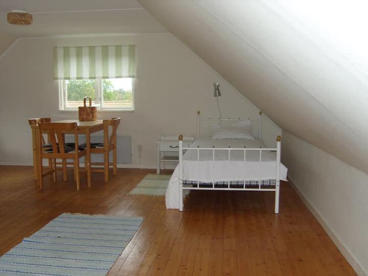 En trappa upp finns det ett stort sovrum/allrum med fyra bäddar. En av enkelsängarna och bord med stolar.