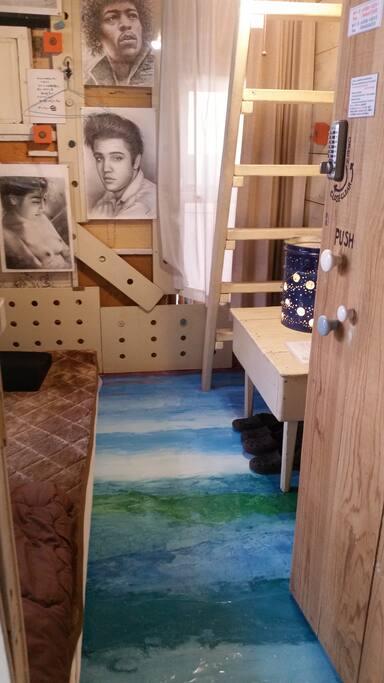 お部屋の入口から見たベッド。沢山のデッサンが。魅力的な女性の絵もあります。