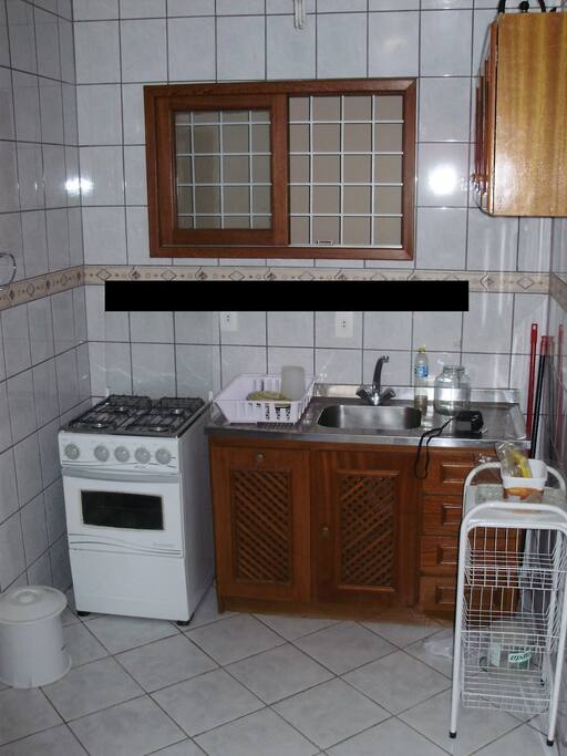 Cozinha mobiliada, fogão, geladeira, mesa e algumas louças