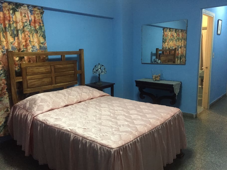 Cama y dos mesas auxiliares a la derecha puerta del baño