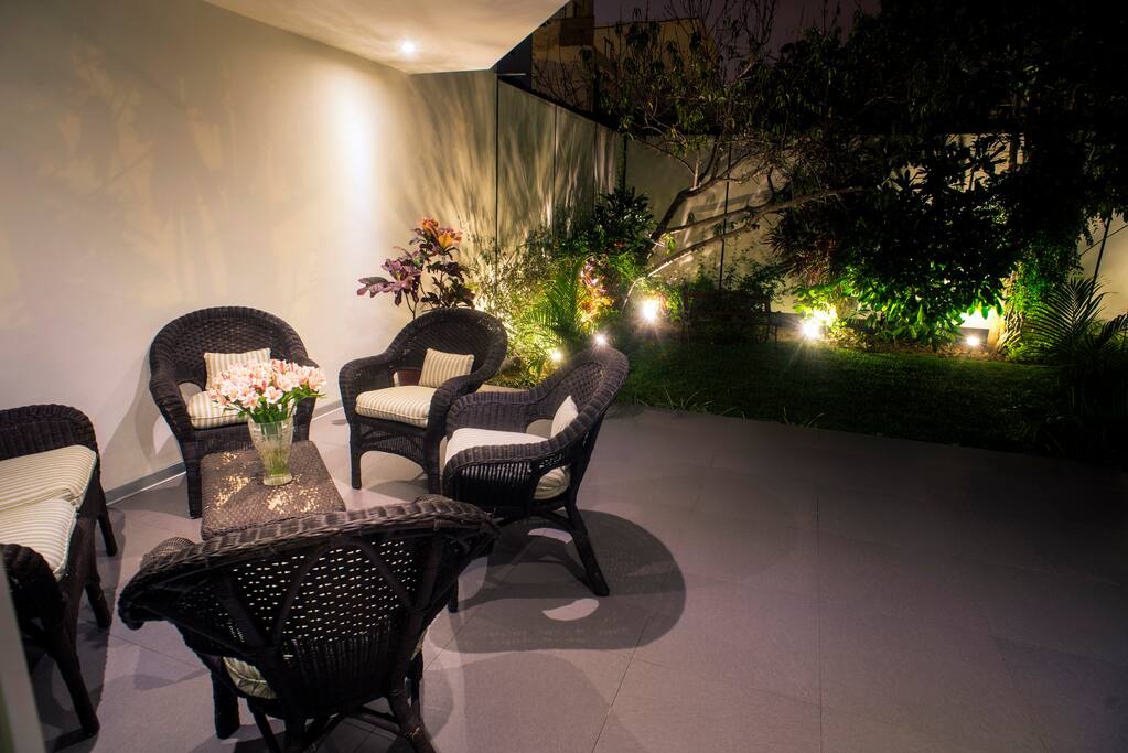 Hermosa terraza que da a un jardín con árboles y flores.