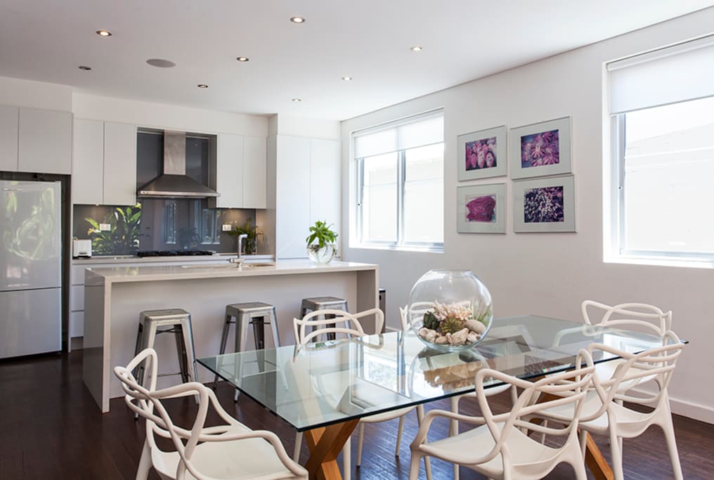 Kitchen and dining area, with bar stools. Main living space flows from kitchen to dining and onto seating area.