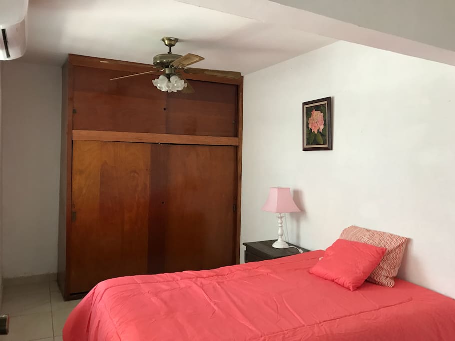 El dormitorio principal, cuenta una cama matrimonial, cuadros de decoración y con una mesita de noche.