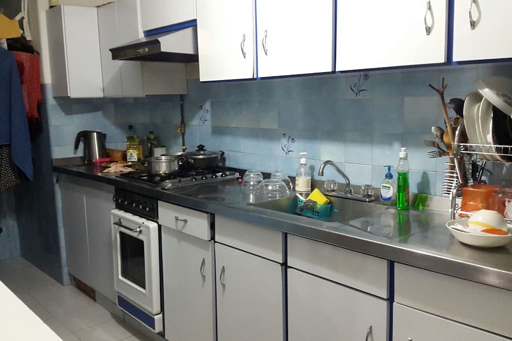 LA cocina cuenta con lo necesario para preparar alimentos, al fondo, una lavadora y sitio de secado