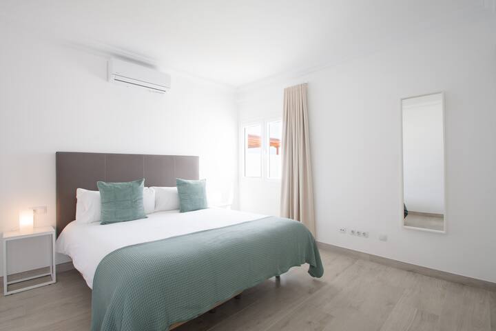 Dormitorio con aire acondicionado, armario, caja fuerte y ropa de cama.