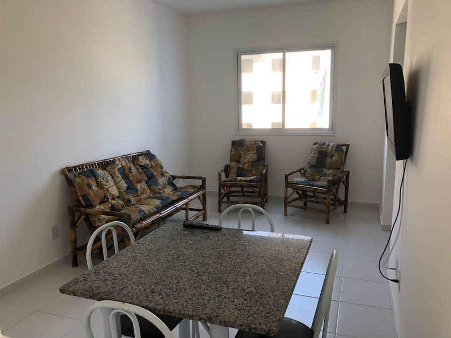 Sala com sofá de 3 lugares, 2 poltronas, mesa com quatro cadeiras e televisão 32 polegadas
