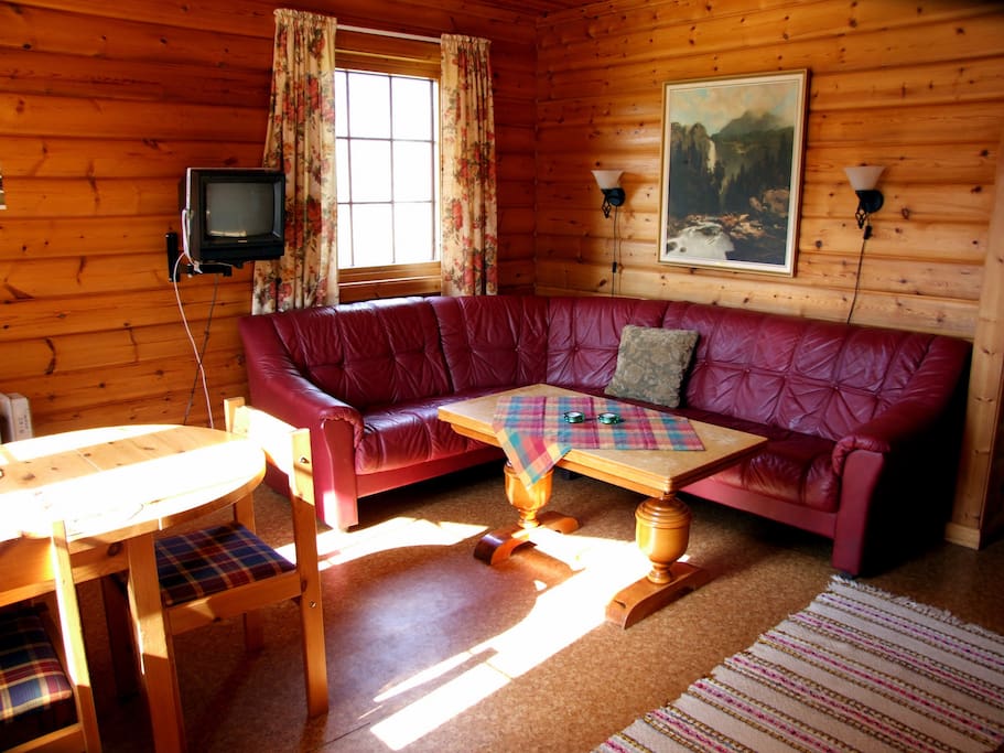 Hjørnesofa og spisebord i stua. TV med tre kanaler (NRK1, 2 og 3)
