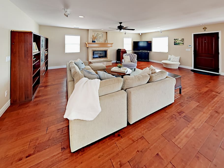 Large sectional sofa and chair sit before a 65" flat screen TV and gas fireplace.