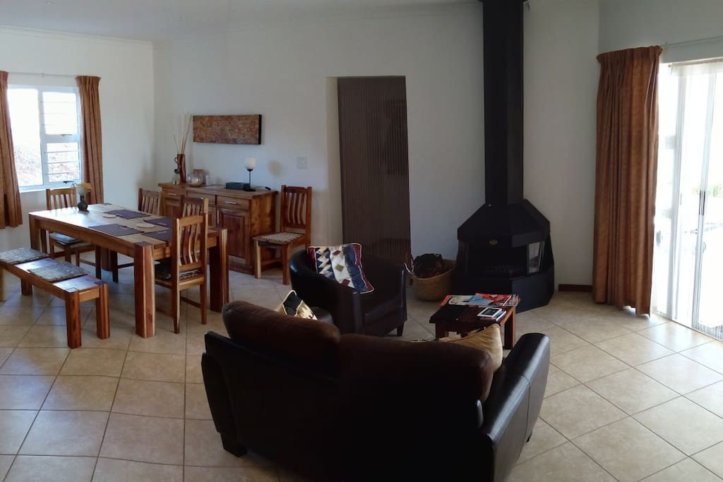 Downstairs living / dining area with fireplace for cold winters. Sliding doors opening on patio with outside build in braai at pool area