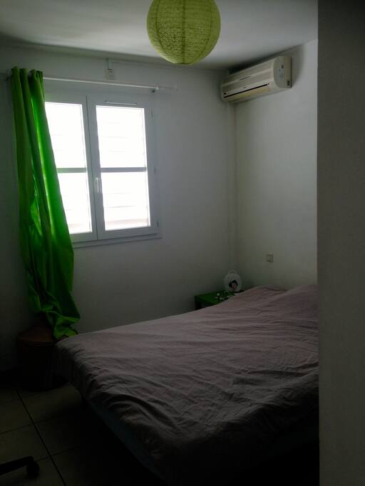 chambre climatisée avec placard de rangements, miroir, chevet et grand lit
