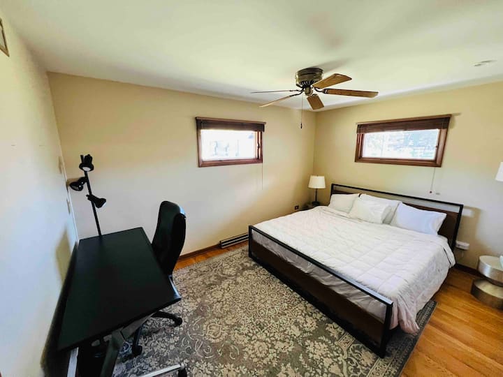 מיטת קינג סייז עם שולחן עבודה גדול וכיסא עור מנהלים.