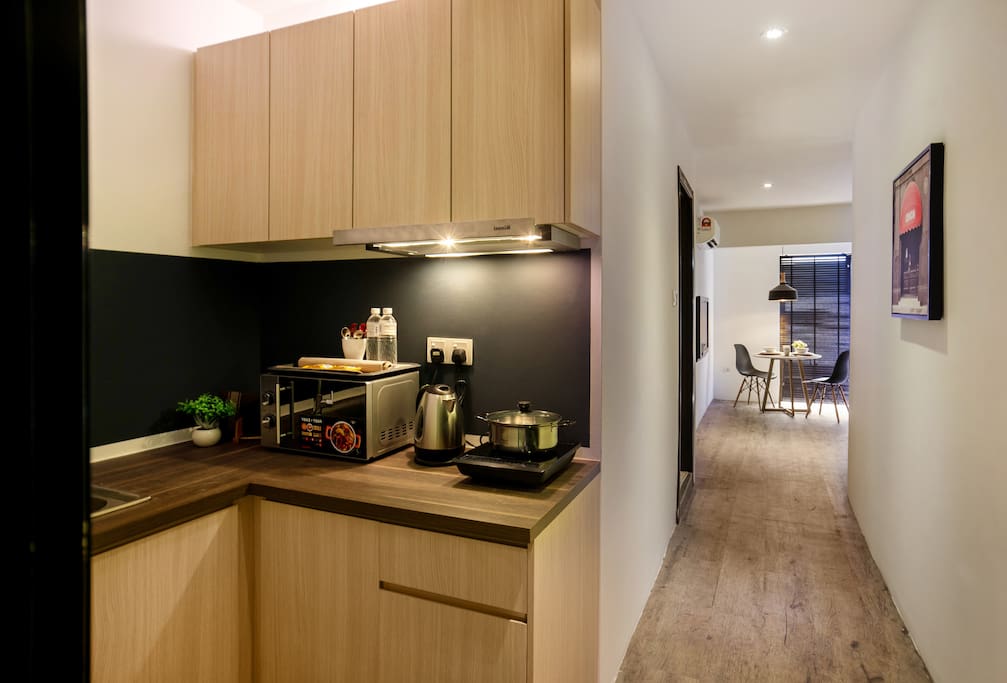 Full kitchen amenities with microwave oven, induction cooker, kitchen hood, pots and pans.