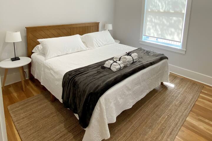 Master bedroom features a king size bed with clean white linens and a microblanket.