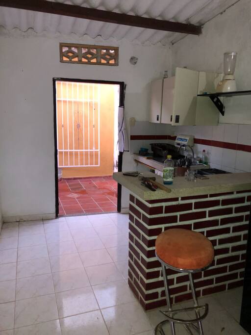 cocina tiene licuadora, estufa con horno, gabinetes, purificador de agua, platos, vasos, cubiertos.