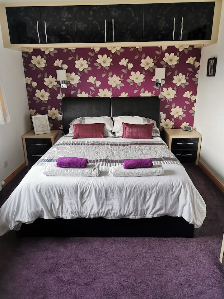 Dormitorio principal con cama matrimonial, iluminación junto a la cama montada en la pared controlada individualmente, armarios junto a la cama y un montón de almacenamiento