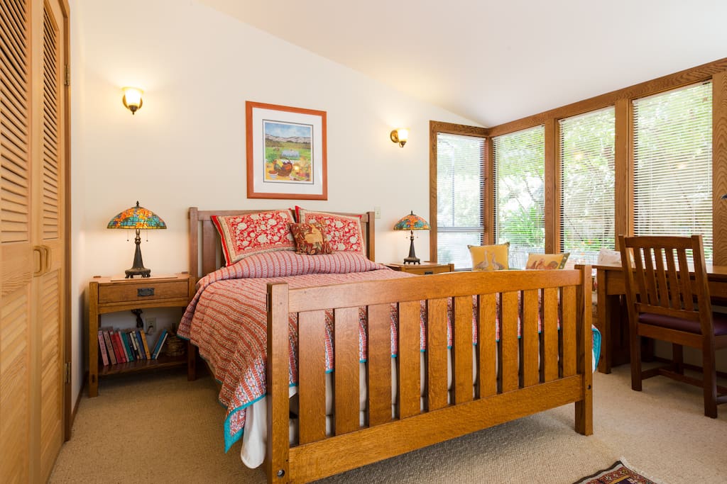 Bedroom with queen-size bed, desk and window seat.