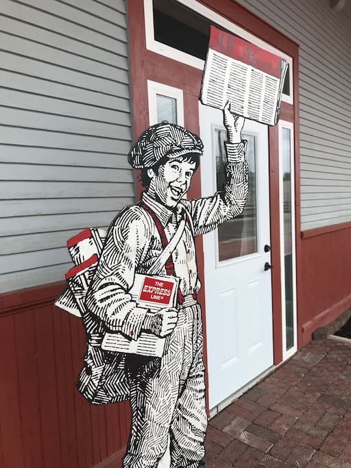 News Paper boy stands outside All Aboard to welcome guest.