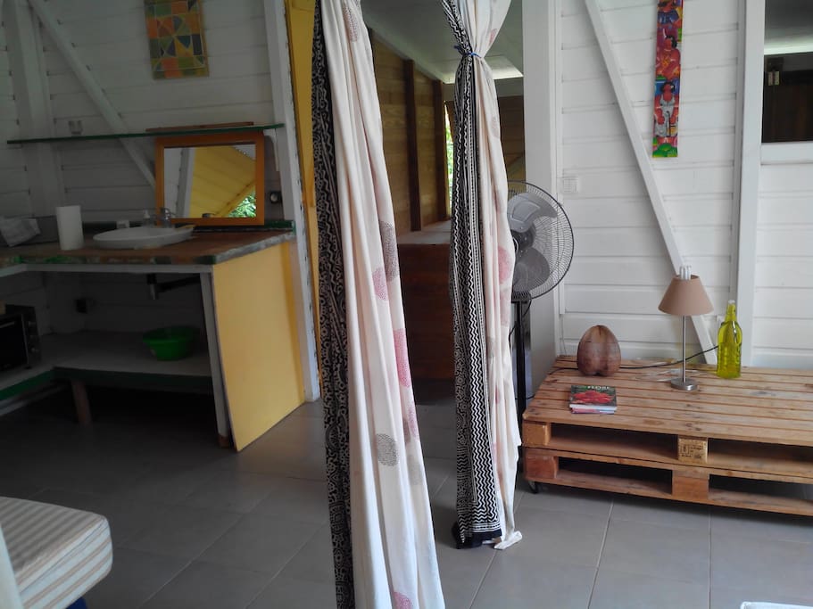 les couchages sont séparés par des rideaux. On voit l'entrée vers la cuisine et la salle de bain.