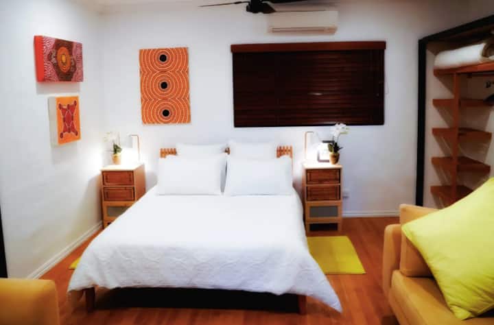 Spacious guest bedroom with comfortable Queen bed, quality bedding,  2 lounges,  local indigenous artwork, generous wardrobes & shelving, adjoining bathroom & an outlook to beautiful  established tropical gardens.