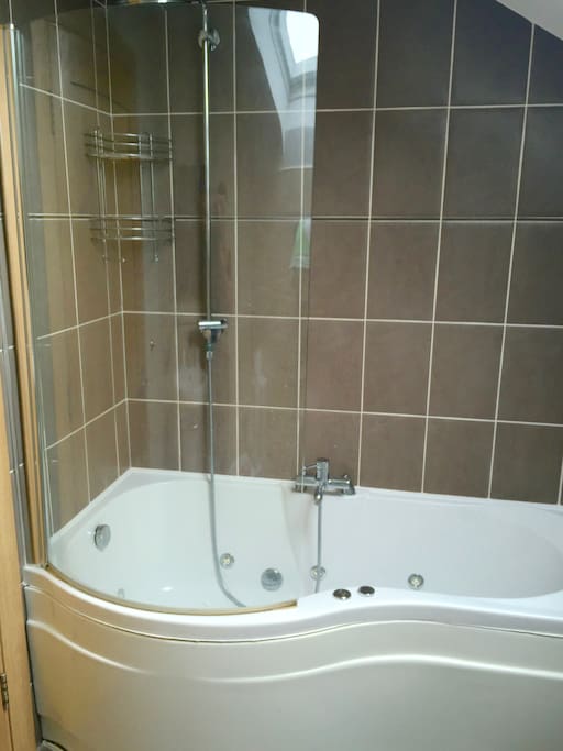 Bathroom with jacuzzi bath and rain shower.
