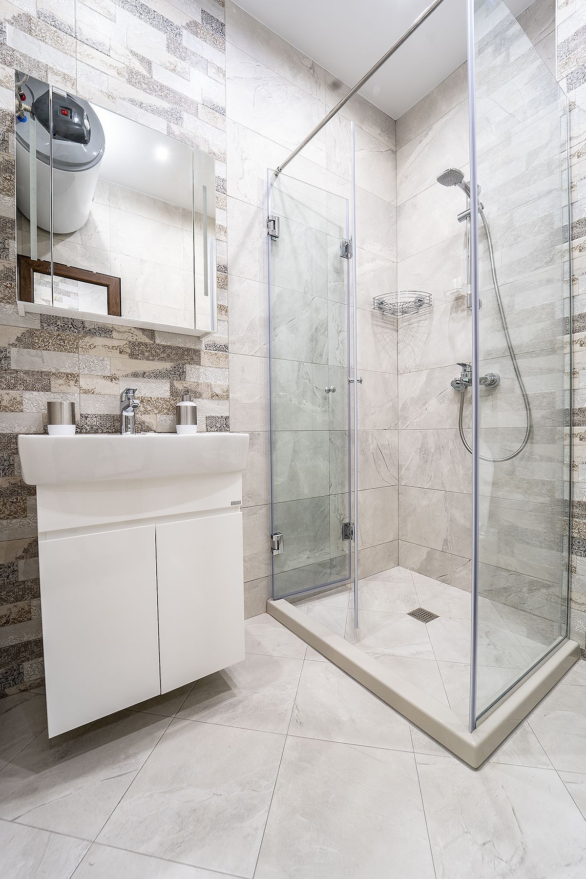 A modern bathroom is showcased with a glass shower enclosure and a sleek sink with storage below. Textured tiles in neutral tones create an elegant backdrop, while a large mirror reflects the space. Minimalistic fixtures enhance the clean and functional design.