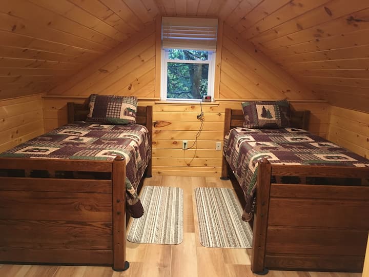 Bedroom with 2 single beds, a rollaway bed under one of them and a dresser.
