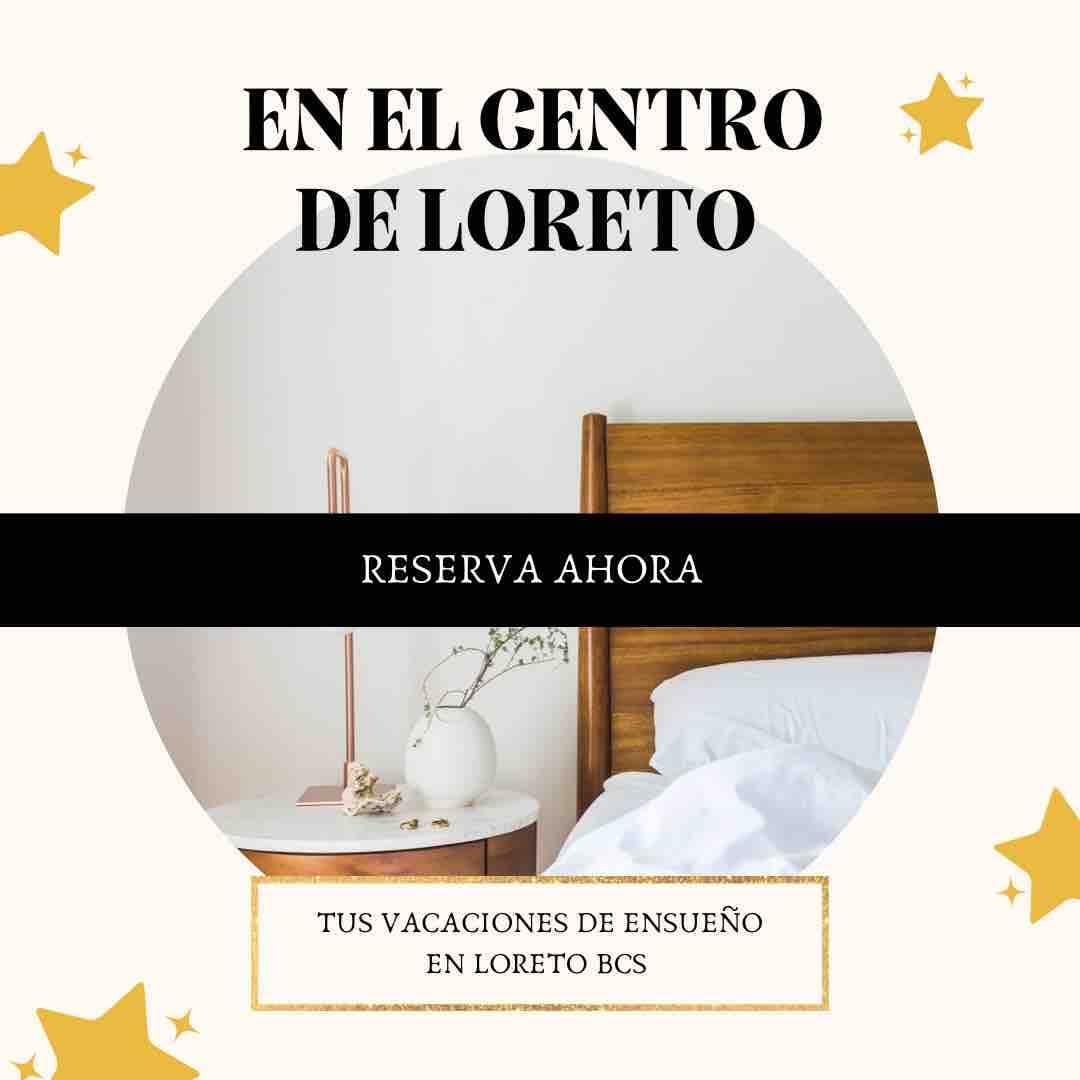 A cozy sleeping area features a wooden headboard and a spacious bed, complemented by a bedside table with a lamp. Soft bedding creates a welcoming atmosphere, while natural light enters through the window, enhancing the room's tranquility.