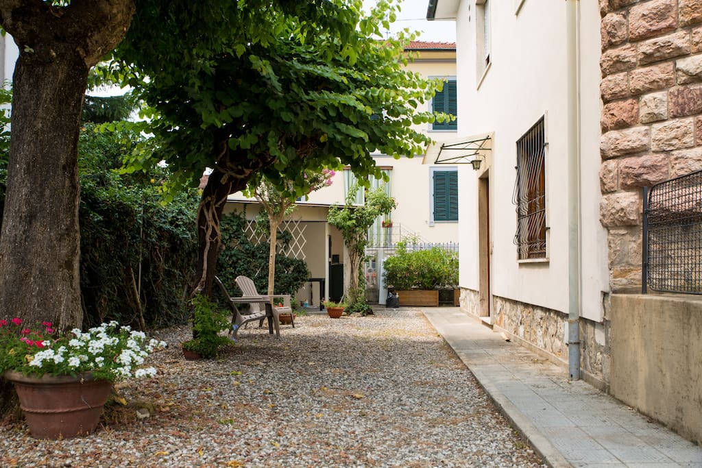 Giardino d'entrata provvisto di due sdraio e un tavolino sotto la veranda.