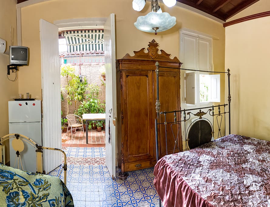 Dos camas dobles estilo colonial, aire acondicionado, baño privado con agua caliente, caja de seguridad y vista a un jardín interior.