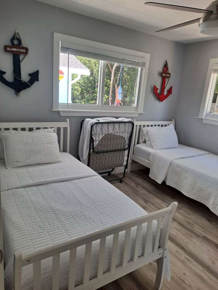 Segundo dormitorio con dos camas individuales, una cama plegable y un pequeño escritorio.