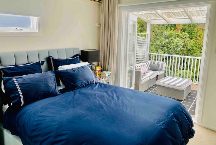 Chambre principale avec lit queen size, balcon privé et coin salon donnant sur le jardin