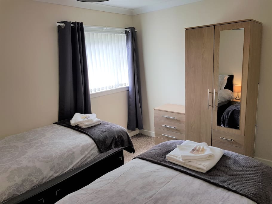 Bedroom 2 Twin Room, with two bedside tables a wardrobe and a chest of drawers (from opposite side)