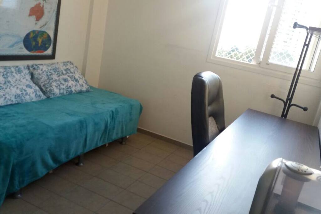 Quarto com ar-condicionado, armário embutido, bicama e mesa com cadeira para estação de trabalho.