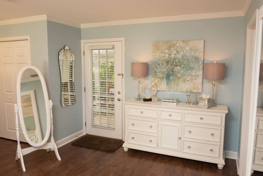 Dresser with full length mirror and door leading to patio