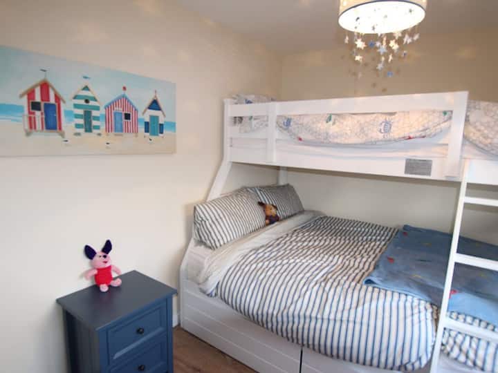 Una cama doble de tamaño completo con una litera individual de tamaño completo arriba, una habitación perfecta tanto para adultos como para niños. 