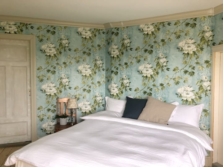 Rymligt sovrum med dubbelsäng. Vacker öppen utsikt över åkrar och skog. Garderob med möjlighet att hänga kläder och få undan resväskan. 