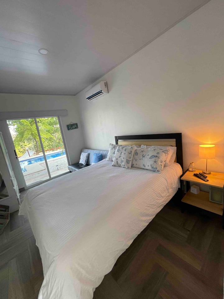 Chambre avec vue spectaculaire et sortie sur la piscine et la forêt, avec un lit queen, un lit superposé avec une lampe, un canapé-lit complet, un placard, une télévision à écran plat avec Netflix et un miroir