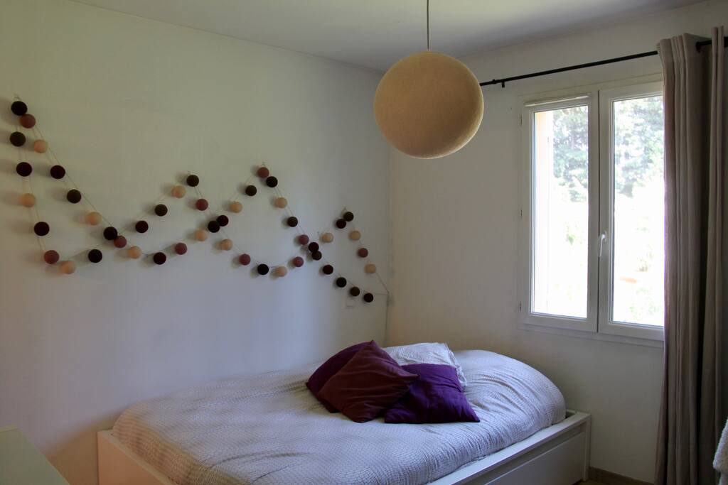 Chambre lumineuse avec vue sur jardin arboré.