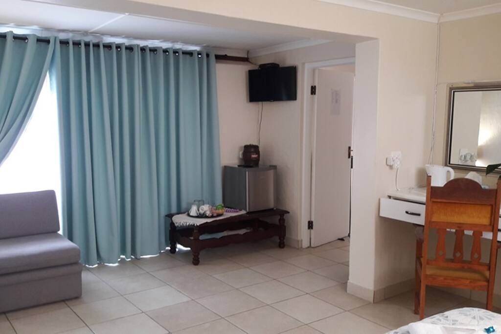 Flat Screen 32" HD Color TV with DSTV. Bar Fridge with Complimentary Bottled Water, Milk, Coffee & Tea Facility with Sugar, Sweetener and Rusks. Two Single Lounge Chairs (can be converted to Sleeper Couches) Exit Door to Balcony and Wooden Look-Out Deck.