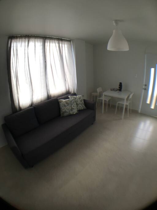 Living Room with Queen Sized Sofa bed. Dining Area next to Balcony door.