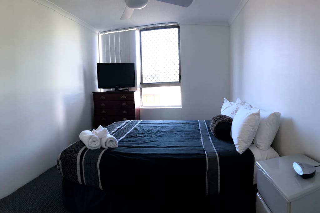 Main bedroom with TV and ceiling fan.
