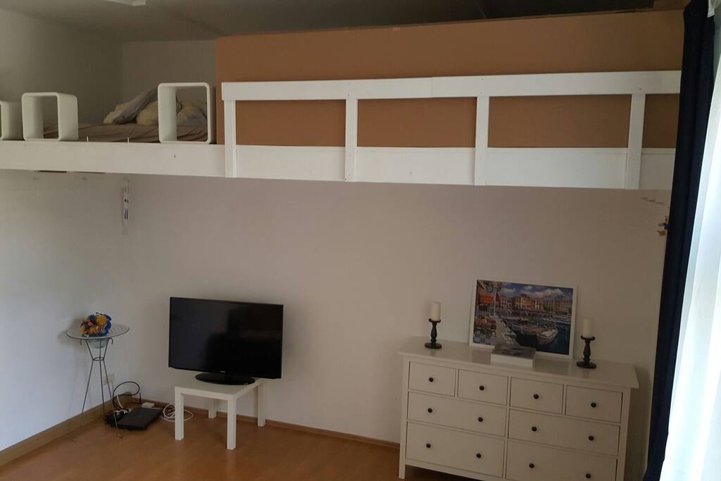 Wohnzimmer mit Hochbett, wo eine Matratze ist, falls man dort schlafen will. TV mit HDMI Kabel ist vorhanden um Laptop anzuschließen.